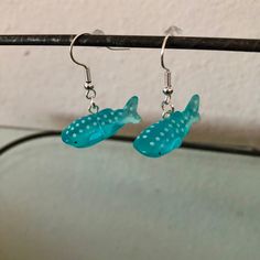 small blue fish earrings hanging from a hook