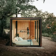 a woman standing in the doorway of a tiny house on top of a dirt hill