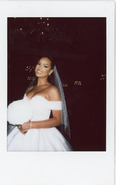 a woman in a white wedding dress posing for a photo with her veil over her shoulder