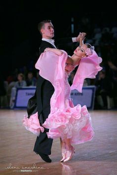 a man and woman in ballroom clothes on a dance floor with their arms around each other