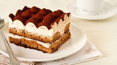 a piece of cake sitting on top of a white plate next to a cup and saucer