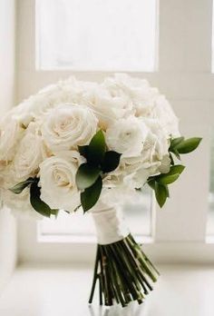 a bouquet of white flowers sitting on top of a table next to a windowsill