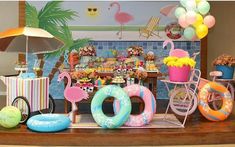 a table topped with lots of balloons and flamingos