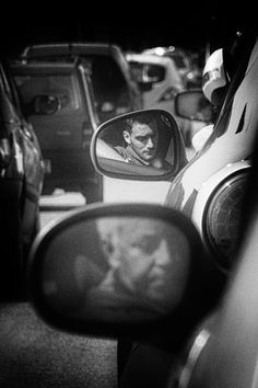 a rear view mirror with the reflection of a man in it's side view mirror