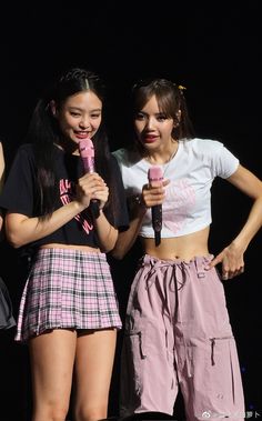 two girls standing next to each other holding microphones