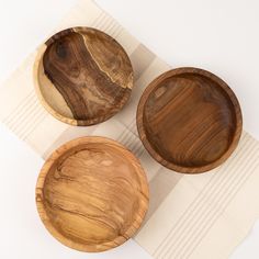 three wooden bowls sitting on top of a white table cloth next to eachother