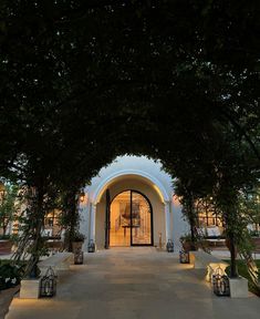 an entrance to a building with trees on both sides and lanterns in the middle at night