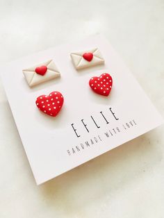 two red and white heart shaped studs on top of a card