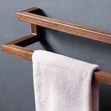 a wooden towel rack with two towels hanging on it's sides and a white towel in the middle