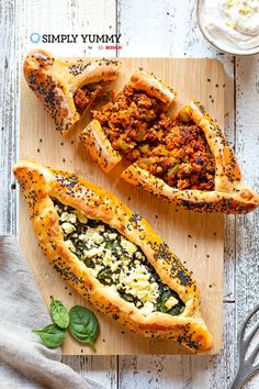 three different types of pies on a cutting board with spinach leaves and other toppings