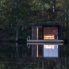 a houseboat floating on top of a lake surrounded by trees and water at night