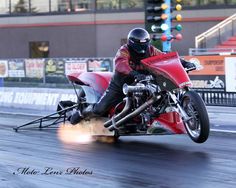 a man riding on the back of a red motorcycle