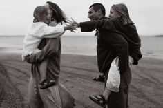 three people are walking on the beach with their arms around each other and one person is holding another persons hand