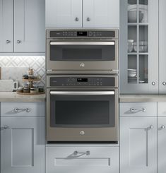 two ovens in a kitchen with white cabinets and gray counter tops, one is built into the wall