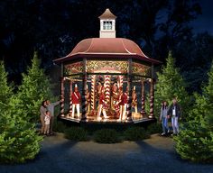 people standing in front of a gazebo with christmas decorations on it at night time