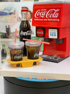 coca - cola machines and drinks are on display in a glass case