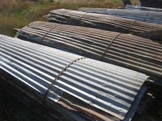 several metal roofing sheets laying on top of each other in an open grassy field