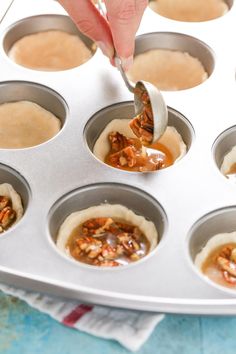 a person spooning some food out of a muffin tin