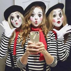 three women dressed as clowns taking a selfie with their cell phone in front of them