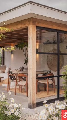 an outdoor dining area with wooden tables and chairs, surrounded by white flowers on the ground