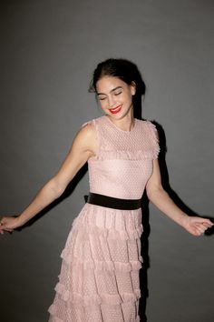 a woman in a pink dress with her arms out and hands extended, posing for the camera