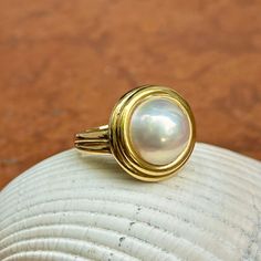 New, but old pieces, never worn, recently acquired from a premiere jeweler located in Minneapolis, MN for many years- a rare opportunity. 18KT yellow gold genuine, double bezel, round, mabe pearl ring Size 6.50 Sizable by us for a fee or your local jeweler Weight: 12.2 grams Band width: 3mm in back 11.50~12mm round mabe pearl Stamped 18k Classic Cabochon Pearl Ring For Formal Occasions, Classic Formal Pearl Ring With Cabochon, Anniversary Yellow Gold Pearl Ring With Cabochon, Formal Cabochon Pearl Ring, Anniversary Cabochon Pearl Ring, Classic Round Pearl Ring With High Luster, Heirloom Pearl Ring With Polished Finish, Gold Oval Cabochon Pearl Ring, Fine Jewelry Pearl Cabochon Ring For Anniversary