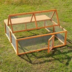 a chicken coop sitting on top of a grass covered field next to a wooden bench