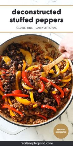 a skillet filled with beef and peppers on top of a marble countertop next to a wooden spoon