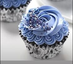 two cupcakes with blue frosting and sprinkles on them are sitting next to each other