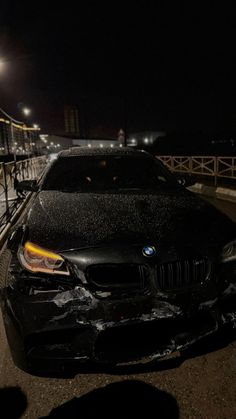 a black car parked on the side of a road in front of a bridge at night