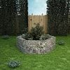 a stone planter sitting in the middle of a lush green yard