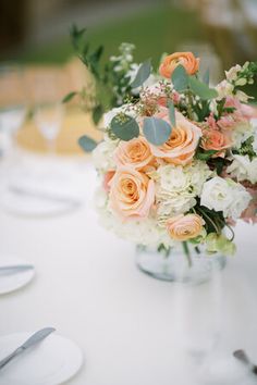 a vase filled with flowers sitting on top of a table covered in white and orange plates