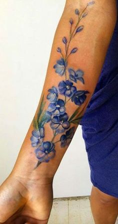 a woman's arm with blue flowers and leaves on the left side of her body