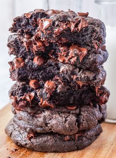 a stack of cookies with chocolate chips on top and a glass of milk in the background