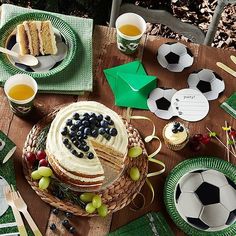 a table topped with plates and cake covered in frosting next to cupcakes