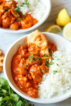 two white bowls filled with food next to lemon wedges and parsley on the side