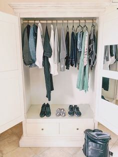 an open closet with shoes and clothes hanging on the rack, next to a black bag