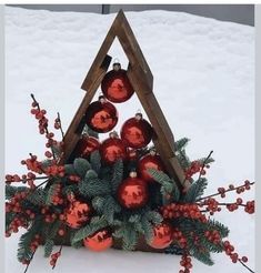 a christmas tree made out of red baubles and greenery in the snow