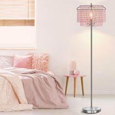 a bedroom with a pink bed and floor lamp next to the bed in front of it