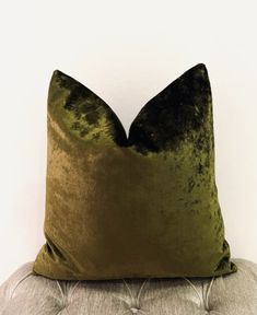 a green velvet pillow sitting on top of a couch