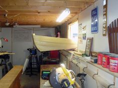 a workbench with some tools on it and a boat hanging from the ceiling