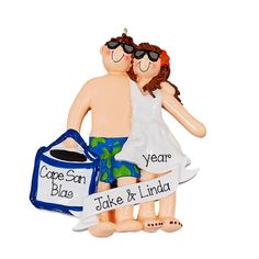 a ceramic ornament depicting two people with sunglasses on their heads, one holding a bag and the other carrying a cooler