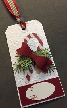 a gift tag with a red bow and evergreen sprig on it that says to ferme