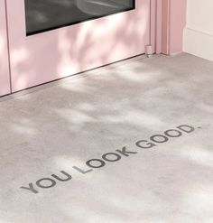 you look good written on the ground in front of a pink door with a window