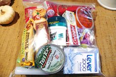 an assortment of snacks and drinks in a plastic bag on a table next to a pumpkin