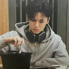 a person with headphones on and holding a bowl in front of them while sitting at a table