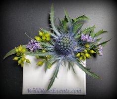 an arrangement of flowers is displayed on a white napkin with blue and green leaves in the center