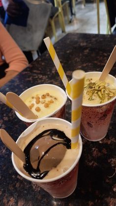 three cups filled with different types of desserts on top of a marble countertop