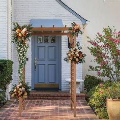 a blue front door surrounded by flowers and greenery