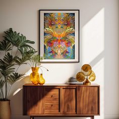 a painting hanging on the wall next to a wooden cabinet with two vases and plants